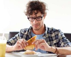 happy-man-eating-sandwich-at-cafe-for-lunch