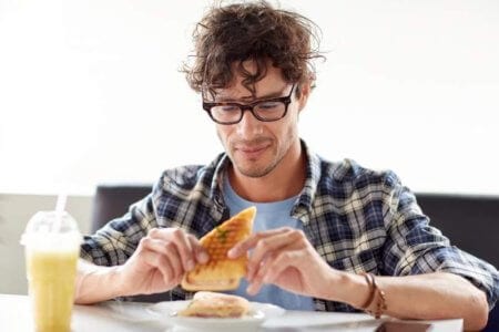 happy-man-eating-sandwich-at-cafe-for-lunch