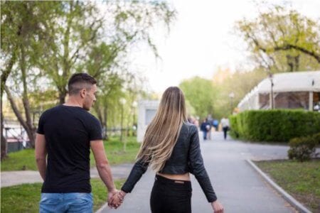 happy-couple-from-behind-holding-hands