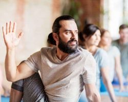 man-with-group-of-people-doing-yoga-at-studio