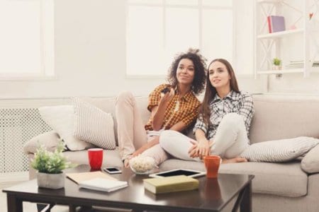 smiling-female-friends-watching-tv-at-home