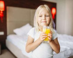 little-girl-with-glass-of-orange-juice-in-bedroom