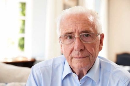 portrait-of-senior-man-sitting-on-sofa-suffering