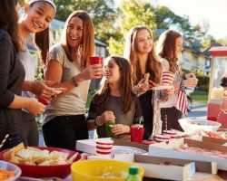 girls-stand-talking-at-a-block-party-food-table