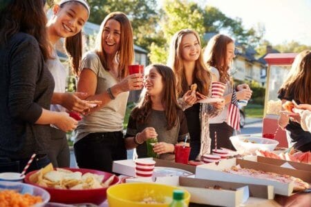 girls-stand-talking-at-a-block-party-food-table
