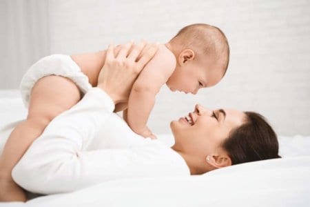 mother-with-baby-on-bed-having-good-time