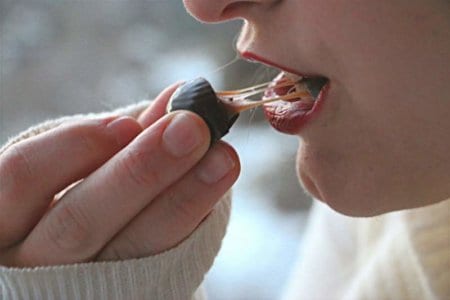 Woman taking a bite out of a chocolate