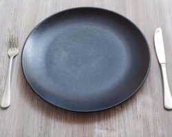 black-plate-with-knife-spoon-on-gray-brown-table